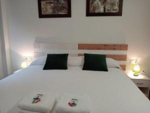 una camera da letto con un letto bianco e due pantofole sopra di Alojamientos Zabala La Piedra en Nájera a Nájera