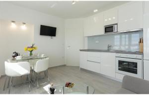 eine Küche mit weißen Schränken und einem Tisch mit Stühlen in der Unterkunft One-Bedroom Apartment In Solin in Solin