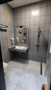 a bathroom with a sink and a shower at Baza noclegowa Mistral in Sieradz