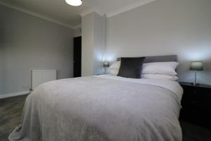 a bedroom with a large bed with white sheets and pillows at Signature - Sunnyside House in Holytown