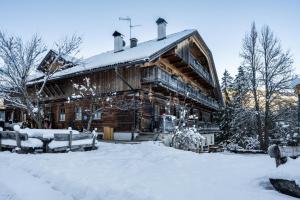 une grande cabane en rondins avec de la neige au sol dans l'établissement Lechnerhof Apt 1, à Braies