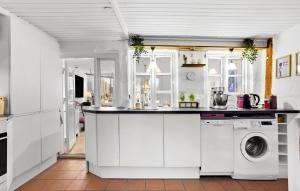 cocina con armarios blancos, lavadora y secadora en 1 Bedroom Awesome Home In Middelfart en Middelfart