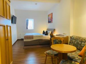 ein Schlafzimmer mit einem Bett, einem Tisch und einem Stuhl in der Unterkunft Hotel Rotgiesserhaus in Kurort Oberwiesenthal
