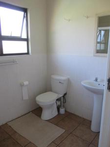 a white bathroom with a toilet and a sink at Sea View in Coffee Bay
