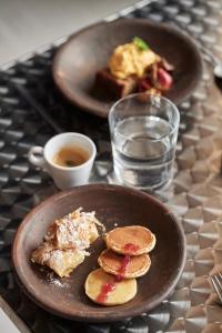 two plates of pancakes and a glass of water and a plate ofoux at The Newel Acropolis in Athens