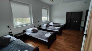 a room with three beds and a couch and two windows at Baza noclegowa Mistral in Sieradz