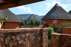 ein Resort mit Strohdächern und einer Steinmauer in der Unterkunft Bama Lodge in Ohrigstad