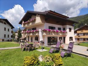 een huis met paarse stoelen en tafels in een tuin bij Appartamenti da Costantino in Padola