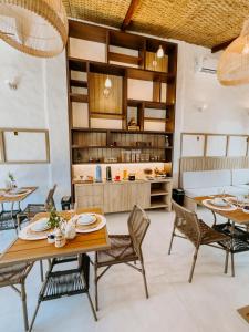 a dining room with tables and chairs and a kitchen at Pousada Vila de Pedras Noronha in Fernando de Noronha