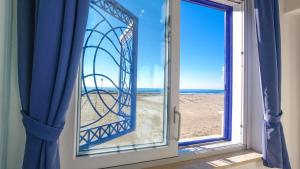 een raam met uitzicht op het strand bij Le Tre Caravelle in Nettuno