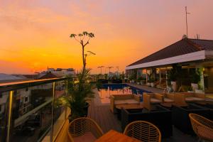 een bar op het dak met tafels en stoelen bij zonsondergang bij Hotel FortunaGrande Malioboro Yogyakarta in Yogyakarta