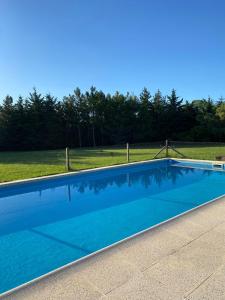 a blue swimming pool with a fence and a field at La Calma Casa Quinta - PISCINA, PARRILLA, WIFI - in Pilar