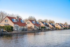una fila de casas junto a un río en De Zilverreiger by Droomvilla, en Langweer