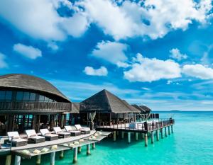 een resort op het water met ligstoelen en de oceaan bij Coco Bodu Hithi in North Male Atoll