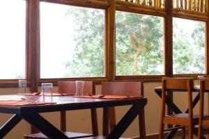 a dining room table with chairs and two windows at GAIRAH RESORT in Mundakāyam