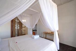 レンボンガン島にあるPaus Putih Hotelの白いカーテン付きの白いベッド(ベッドルーム内)
