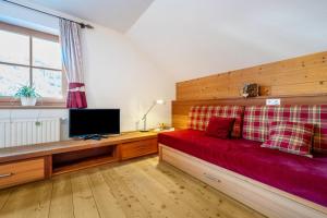 a bedroom with a red bed and a tv at Lechnerhof Apt 3 in Braies