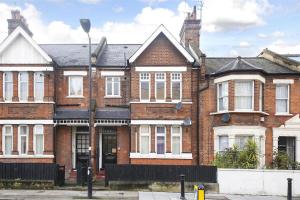 a brick house with white windows on a street at London Zone 2, Easy Travel in London