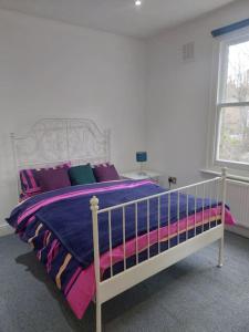 1 dormitorio con 1 cama grande con almohadas moradas en London Zone 2, Easy Travel, en Londres