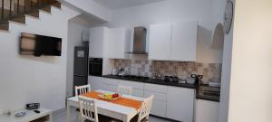 a kitchen with white cabinets and a table and chairs at Happy Home in Pozzallo