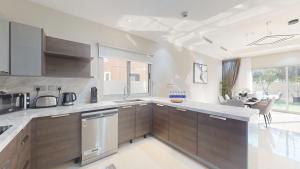 a kitchen with wooden cabinets and a dining room at Primestay - VILLA 4 - JVC in Dubai