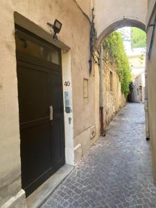 eine Gasse mit einer schwarzen Tür an der Seite eines Gebäudes in der Unterkunft Escapades L'Isloises au cœur de L'Isle-sur-la-Sorgue. in LʼIsle-sur-la-Sorgue