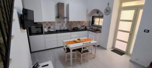 a kitchen with white cabinets and a table with chairs at Happy Home in Pozzallo