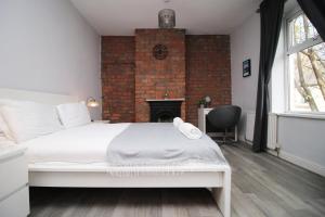 a bedroom with a white bed and a brick wall at Parking | 2BR | Luxurious in Cardiff