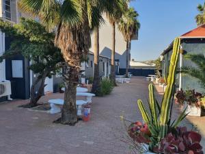 a patio with benches and palm trees and buildings at Sirwine Hotel, Bar and Restuarant in Windhoek