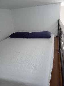 a white bed with a blue pillow on it at Tiny House Idaman Kuala Terengganu with Private House in Kuala Terengganu
