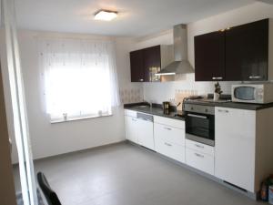 a kitchen with white cabinets and a window at Apartments Bora in Ližnjan