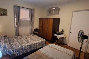 a hotel room with two beds and a desk with a fan at Ñuñoa Sunrise B&B in Santiago