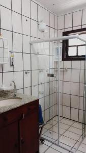 a white tiled bathroom with a sink and a shower at Morada do mar in Santa Cruz Cabrália
