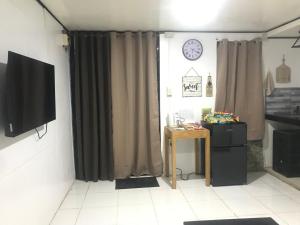 Habitación con cortinas, mesa y TV. en Central Hub Homestay, en Puerto Princesa City