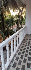 a white railing with palm trees in the background at Mahalaxmi Guest House in Gokarna