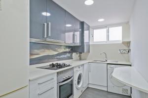 een keuken met witte kasten en een wasmachine en droger bij Apartamento soleado y acogedor in Barcelona
