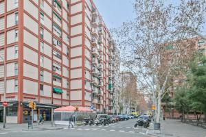 een hoog rood gebouw in een stadsstraat met auto's bij Apartamento soleado y acogedor in Barcelona