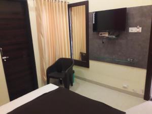 a bedroom with a chair and a television on the wall at HOTEL SAI MEERA PALACE in Shirdi
