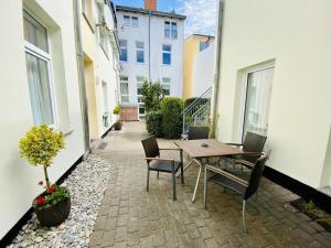 een patio met een tafel en stoelen op een binnenplaats bij Appartement Schwalbenflug in Warnemünde