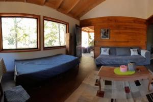 1 dormitorio con cama, sofá y mesa en Casa Bosque Palguín, en Palguín