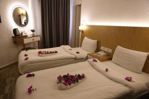 two beds in a hotel room with flowers on them at Eden Hotel in Bodrum City