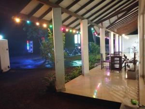 a covered patio at night with a table and chairs at Hotel Panchavaasa in Kurundankulama