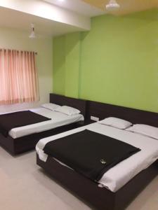 two beds in a room with green walls at HOTEL SAI MEERA PALACE in Shirdi