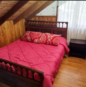 a bed with a red comforter in a room at Cabaña Pachamama in Caburgua