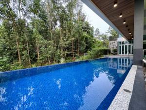 uma piscina de beiral infinito numa casa com água azul em Seri Kembangan Equine Villa with Pool by Iconique em Seri Kembangan