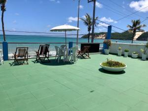 a patio with chairs and an umbrella and the ocean at Ponta Negra Suites & Apart in Natal