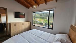 a bedroom with a bed and a large window at Finca la Esperanza Casa para 7 Personas Ubaté Cundinamarca in Ubaté