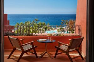 una mesa y sillas en un balcón con vistas al océano en Tivoli La Caleta Resort, en Adeje