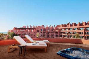 Tivoli La Caleta Resort في أديخي: شرفة مع كرسيين وحوض استحمام ساخن على مبنى