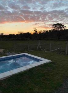 ein Pool im Gras mit Sonnenuntergang im Hintergrund in der Unterkunft Hermosa Casa en San Bernardino in San Bernardino